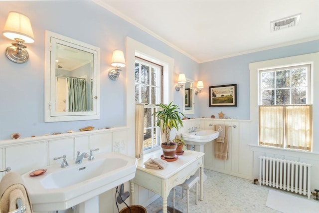 full bathroom featuring visible vents, two sinks, wainscoting, radiator heating unit, and ornamental molding