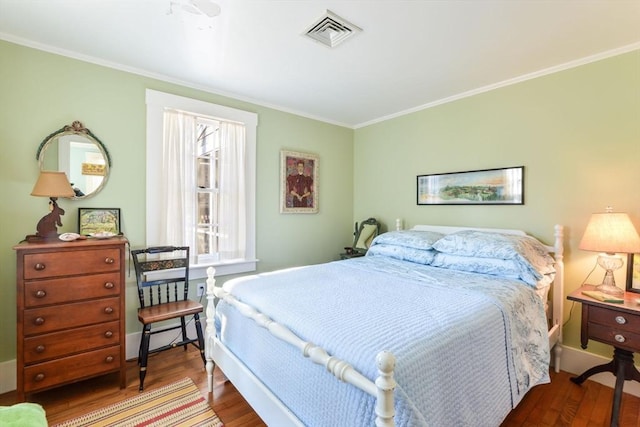 bedroom with baseboards, visible vents, wood finished floors, and ornamental molding