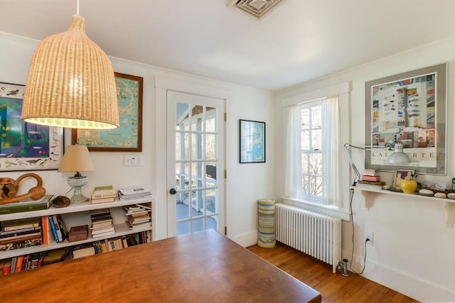 doorway with ornamental molding, visible vents, radiator heating unit, and wood finished floors