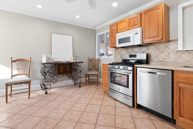 kitchen with backsplash, light tile patterned floors, ornamental molding, and appliances with stainless steel finishes