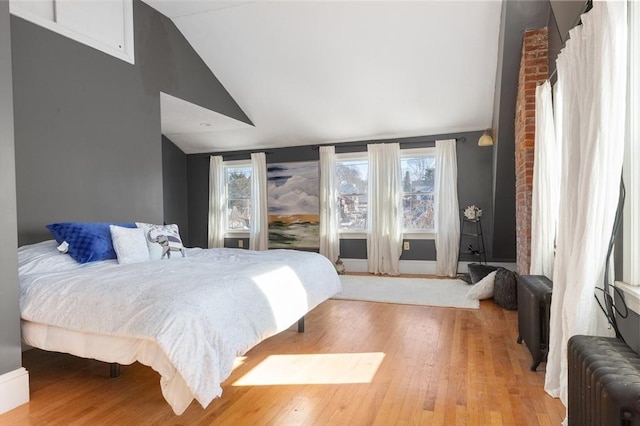 bedroom with multiple windows, radiator, and vaulted ceiling