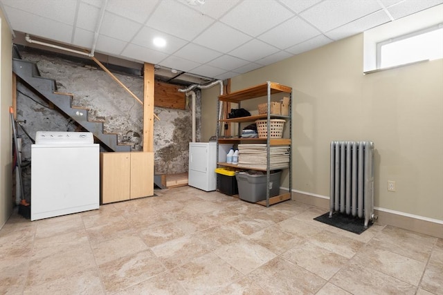 basement featuring a paneled ceiling, radiator heating unit, and washer and clothes dryer