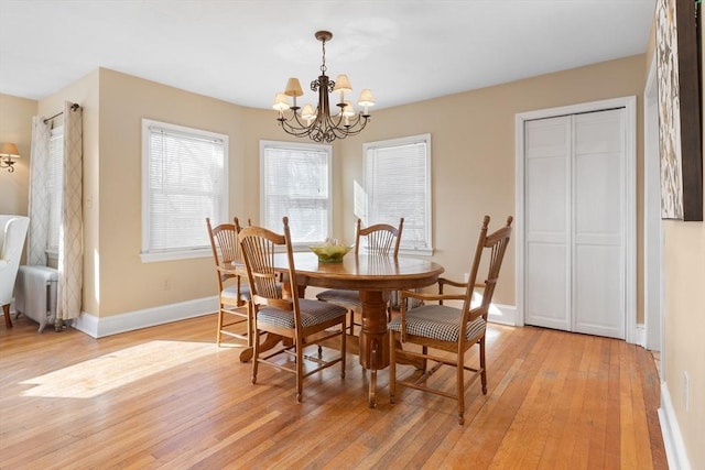 dining space with light hardwood / wood-style flooring and a chandelier