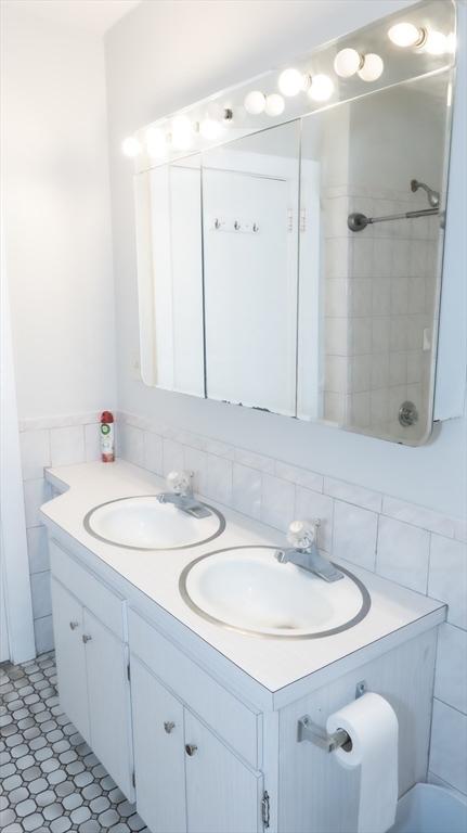 bathroom with double vanity and tile walls