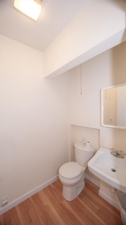 bathroom featuring wood finished floors, toilet, baseboards, and a sink