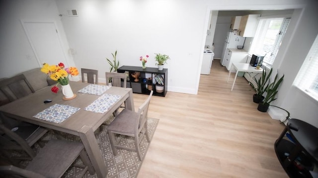 dining room with light wood-style flooring, plenty of natural light, washer / clothes dryer, and baseboards
