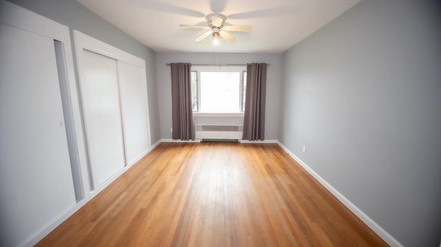 unfurnished bedroom featuring light wood-style flooring, baseboards, ceiling fan, and multiple closets