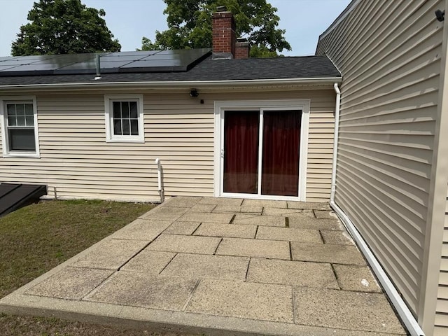 16 Firglade Dr, Attleboro, MA 02703 - property entrance featuring a patio area, solar panels, a chimney, and roof with shingles