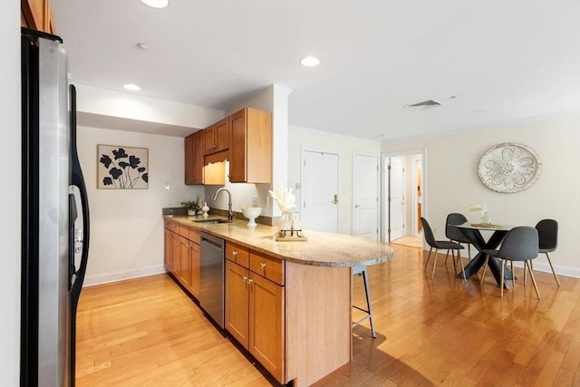 kitchen featuring stainless steel appliances, a kitchen bar, baseboards, a sink, and crown molding