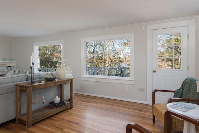 living area with baseboards, wood finished floors, and crown molding