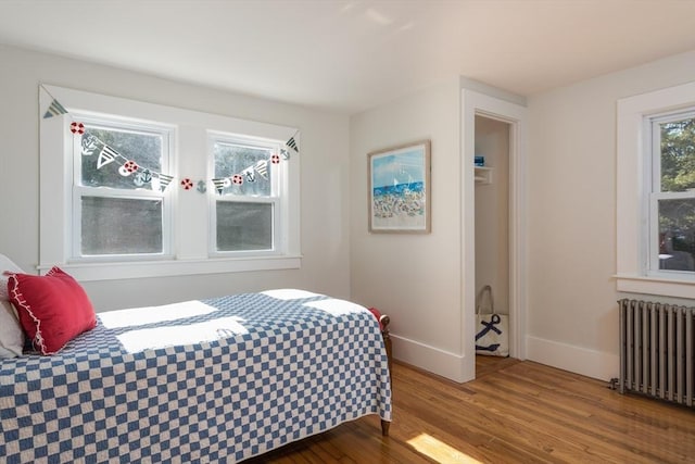 bedroom with baseboards, radiator heating unit, and wood finished floors