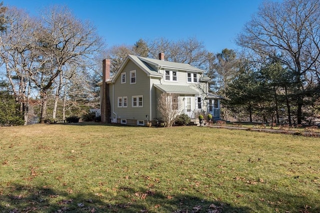 rear view of house with a chimney and a yard