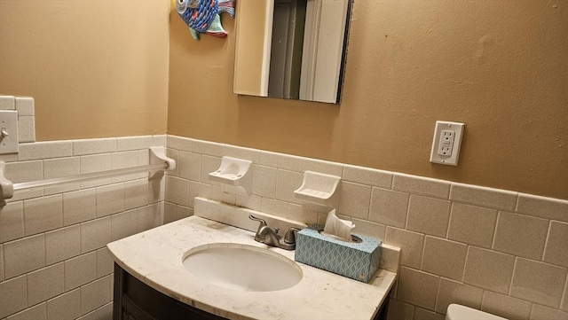 half bathroom with tile walls, wainscoting, and vanity