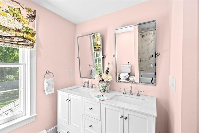 bathroom with double vanity, toilet, and washtub / shower combination