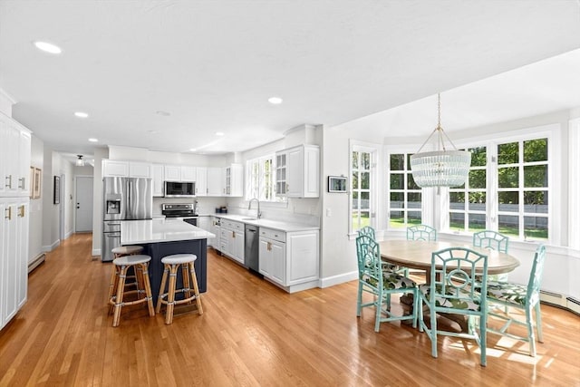 kitchen with appliances with stainless steel finishes, a sink, light wood-type flooring, a chandelier, and a kitchen bar