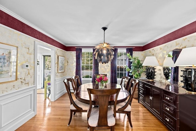 dining space featuring wallpapered walls, wainscoting, light wood-style flooring, and ornamental molding