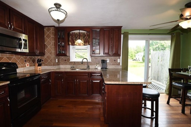 9 Lydon Ln Unit D2, Halifax, MA 02338 - kitchen with stainless steel microwave, black range with electric stovetop, dark wood-style floors, a peninsula, and a breakfast bar area