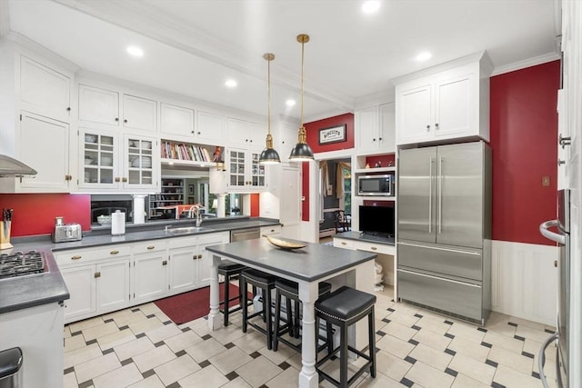104 Main St, Topsfield, MA 01983 - kitchen featuring appliances with stainless steel finishes, a sink, ornamental molding, dark countertops, and white cabinetry