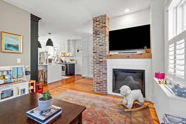 living room featuring light wood finished floors, a large fireplace, and recessed lighting
