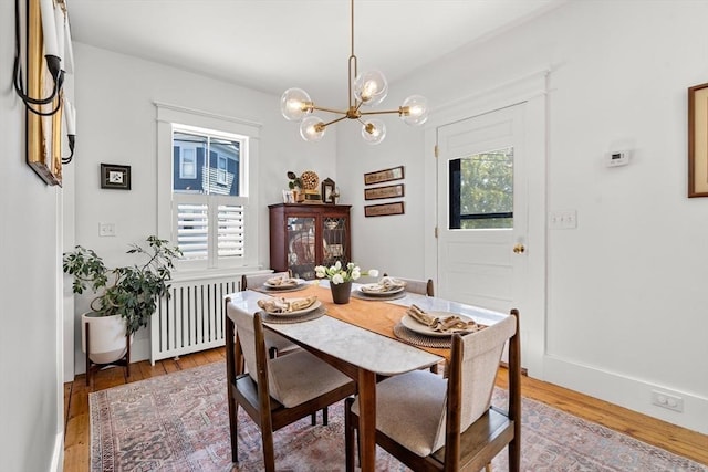 dining area with radiator, an inviting chandelier, light wood-type flooring, and a healthy amount of sunlight