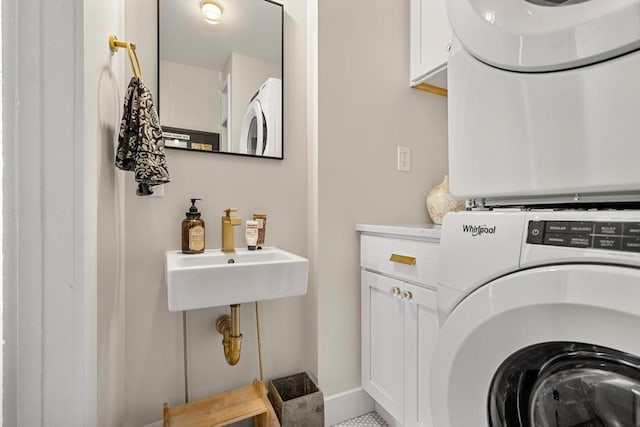 laundry area with stacked washer / drying machine, cabinet space, and baseboards