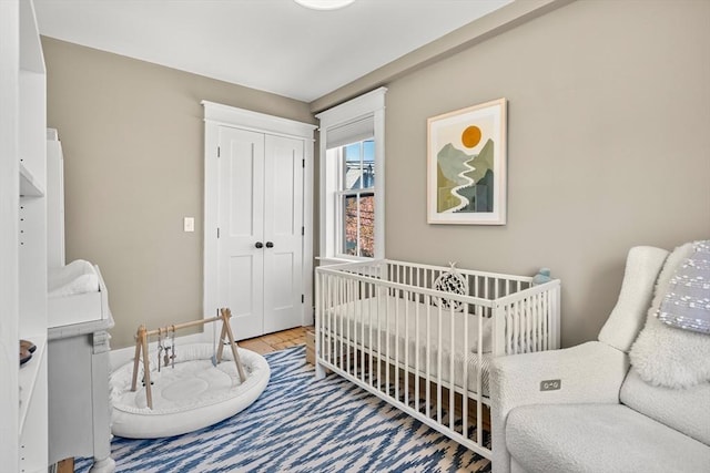 bedroom featuring a closet, a crib, and wood finished floors