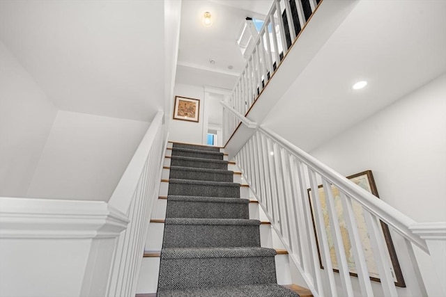 stairway featuring recessed lighting and a towering ceiling