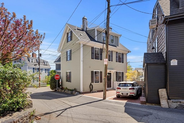 exterior space with a shingled roof and a chimney