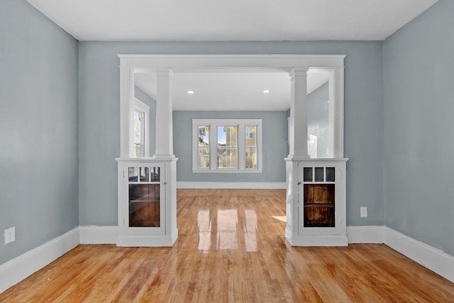 unfurnished living room featuring light hardwood / wood-style flooring and decorative columns