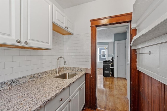 kitchen with white cabinetry, sink, and light stone counters