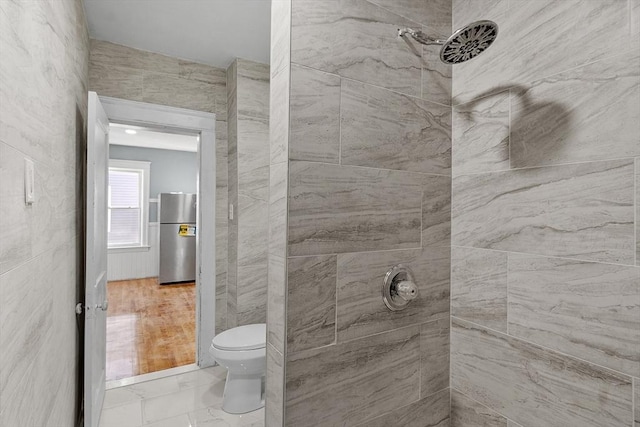 bathroom with a tile shower and toilet