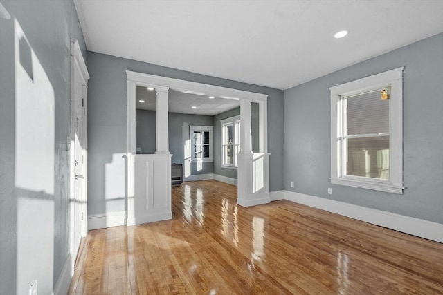 empty room with decorative columns and light hardwood / wood-style flooring