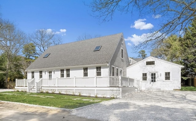 71 Netock Ave, Oak Bluffs, MA 02557 - view of front facade with a wooden deck, gravel driveway, a front yard, and roof with shingles