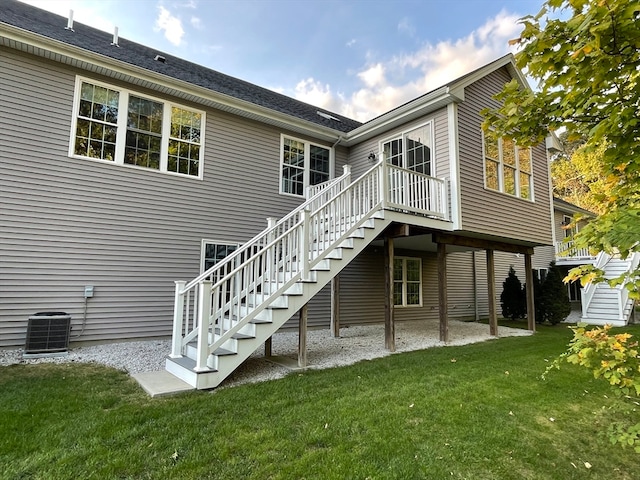 rear view of property with central AC unit and a lawn