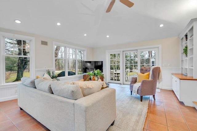 living area with a wainscoted wall, plenty of natural light, and visible vents