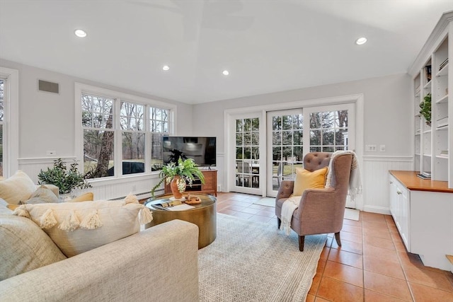 living area with light tile patterned flooring, visible vents, baseboard heating, and wainscoting