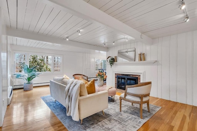 living room featuring beam ceiling, a brick fireplace, wood finished floors, and track lighting