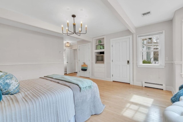 bedroom with visible vents, a baseboard heating unit, multiple closets, an inviting chandelier, and wood finished floors