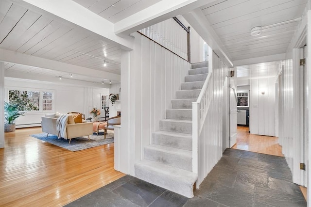 stairway featuring beam ceiling, wood finished floors, wood ceiling, and baseboard heating