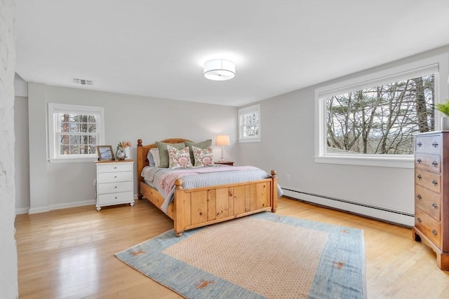 bedroom with multiple windows, visible vents, light wood-type flooring, and a baseboard radiator