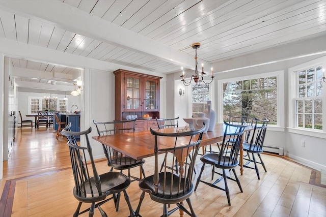 dining area featuring beam ceiling, a notable chandelier, light wood-style flooring, and a baseboard radiator