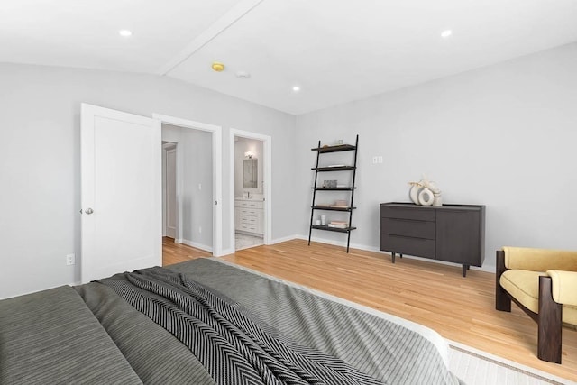 bedroom with ensuite bath, vaulted ceiling, and light hardwood / wood-style floors