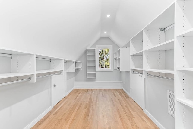 spacious closet with hardwood / wood-style floors and vaulted ceiling