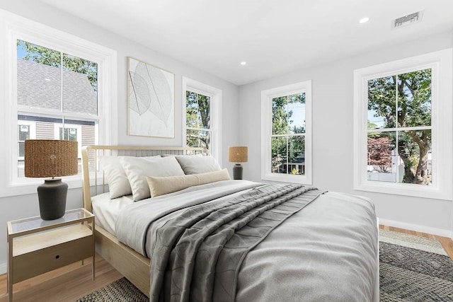 bedroom with multiple windows and hardwood / wood-style floors