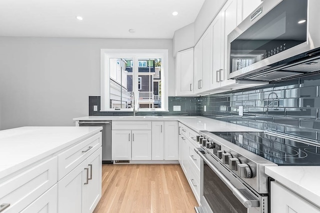 kitchen featuring white cabinetry, backsplash, stainless steel appliances, and light hardwood / wood-style floors