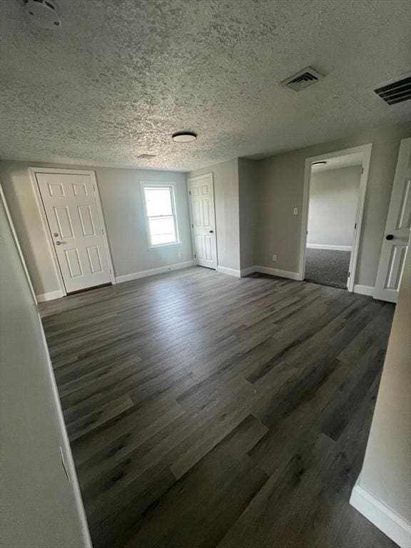 unfurnished room with dark hardwood / wood-style floors and a textured ceiling