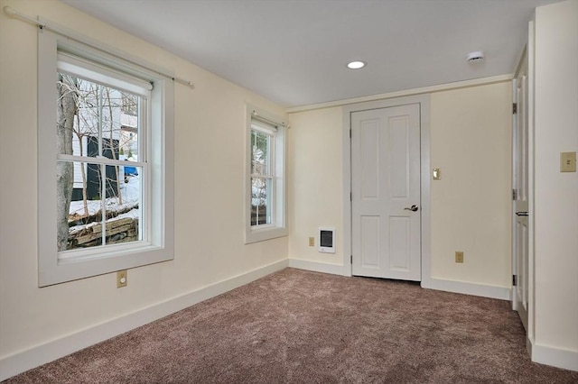 spare room featuring baseboards, carpet floors, a healthy amount of sunlight, and heating unit