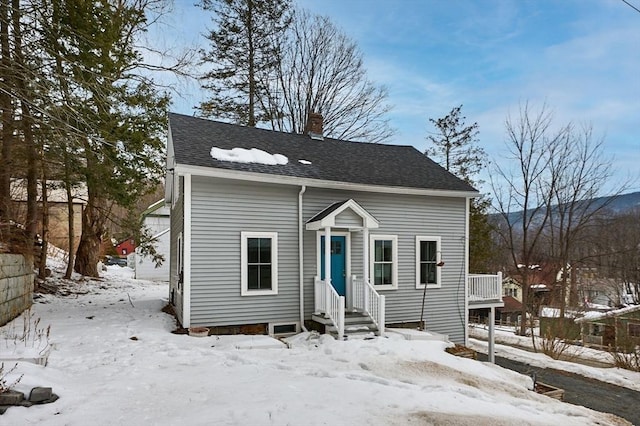 bungalow-style home featuring roof with shingles and a chimney