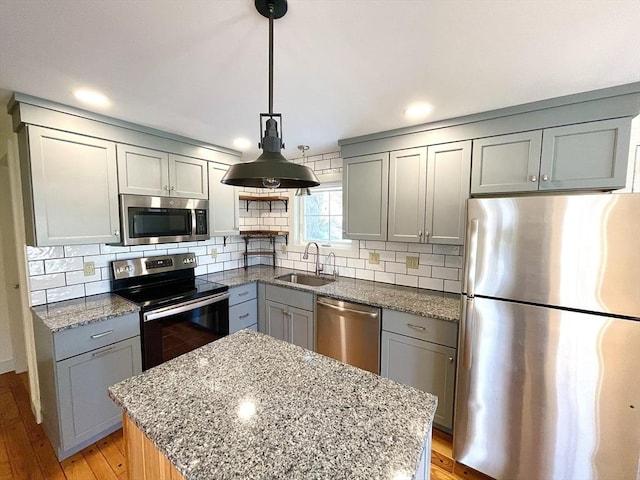 kitchen with backsplash, gray cabinets, stainless steel appliances, and a sink