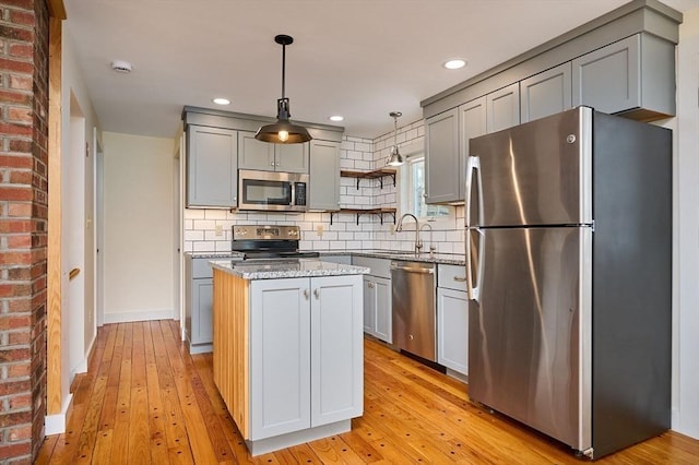 kitchen featuring gray cabinetry, open shelves, a center island, appliances with stainless steel finishes, and light wood finished floors